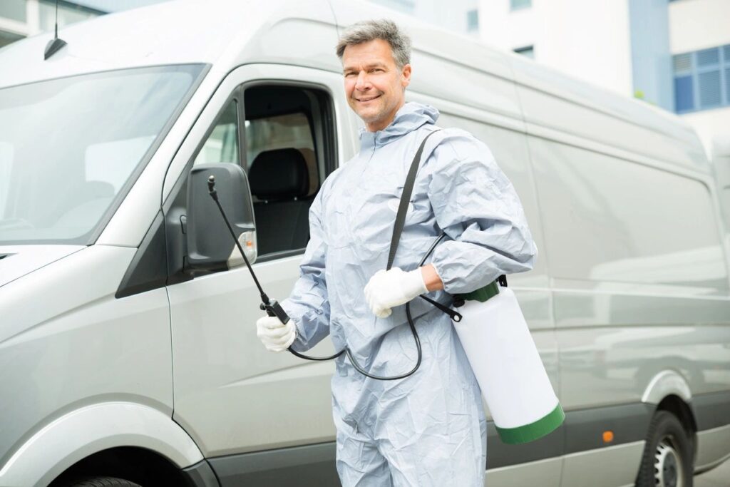 Pest control worker posing in front of van