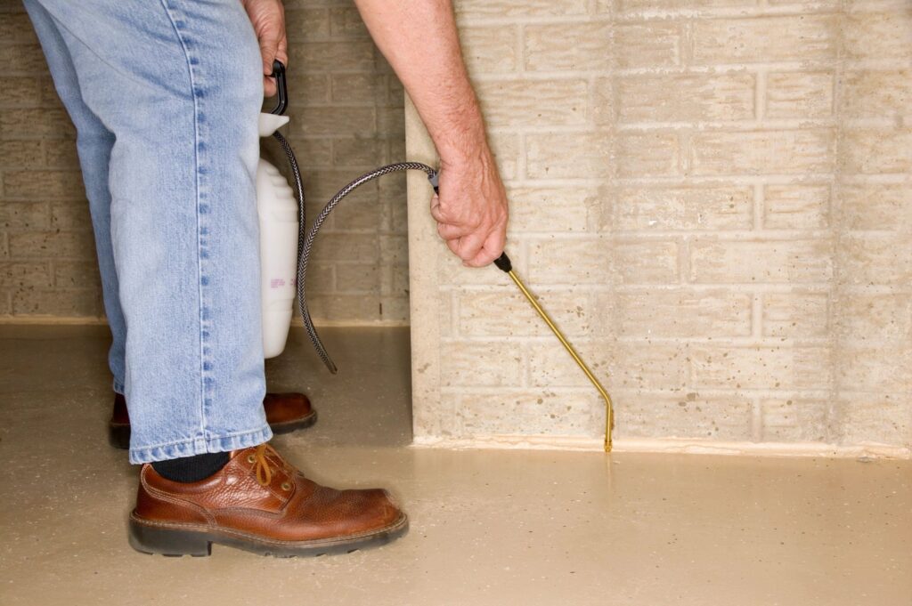 Man spraying pesticide on building wall
